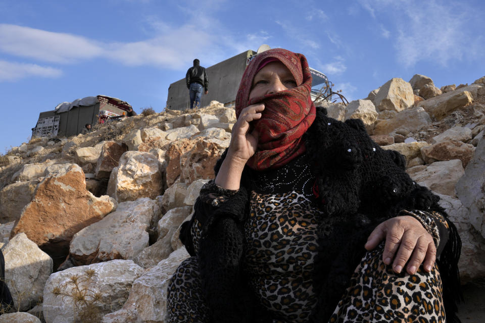 A Syrian refugee woman sits on rocks, as she waits at a gathering point to cross the border back home to Syria, in the eastern Lebanese border town of Arsal, Lebanon, Wednesday, Oct. 26, 2022. Several hundred Syrian refugees boarded a convoy of trucks laden with mattresses, water and fuel tanks, bicycles – and, in one case, a goat – Wednesday morning in the remote Lebanese mountain town of Arsal in preparation to return back across the nearby border.(AP Photo/Hussein Malla)