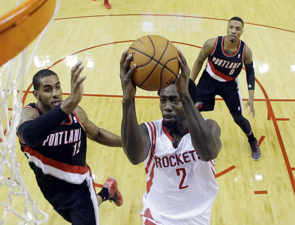 Houston Rockets' Patrick Beverley shoots past Portland Trail Blazers' LaMarcus Aldridge (12) and Damian Lillard during the first half in Game 1 of an opening-round NBA basketball playoff series, Sunday, April 20, 2014, in Houston. (AP Photo/David J. Phillip)