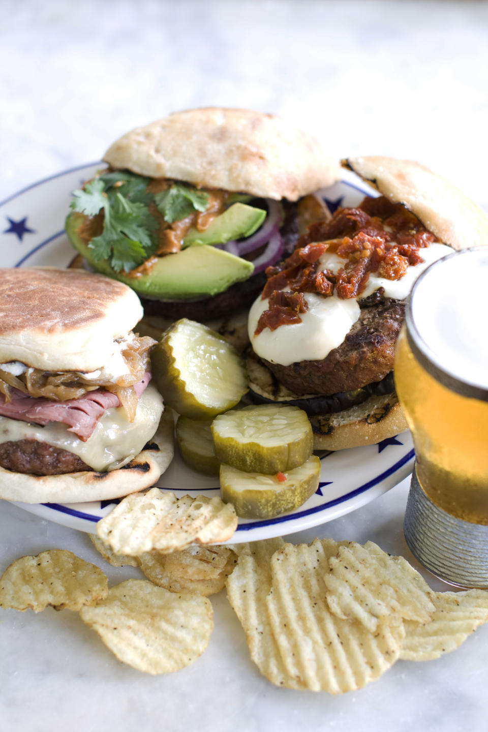In this image taken on June 10, 2013, clockwise from top, The Thai, The Eggplant Parm and The New Yorker, burgers are shown on a plate in Concord, N.H. (AP Photo/Matthew Mead)