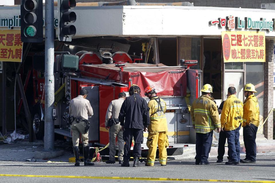Firefighters and other officials work the scene of an accident where two firetrucks answering a call collided en route to a fire Wednesday, April 16, 2014, in Monterrey Park, Calif. The collision sent one firetruck careening into a restaurant, leaving 14 people, including several firefighters, injured. (AP Photo/Nick Ut)