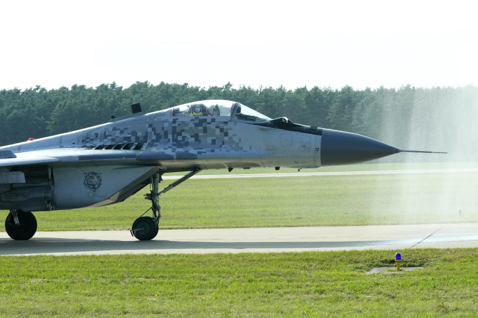 FILE - Slovak Air Force MiG-29 goes through a water gate during an airshow in Malacky, Slovakia, Saturday, Aug. 27, 2022. Former Soviet satellite Slovakia has been a NATO member since 2004, but the reality of belonging to the world’s biggest military alliance really kicked in after Russia’s invasion of Ukraine a year ago. The small central European country now hosts thousands of NATO troops while allied aircraft patrol its skies. (AP Photo/Petr David Josek,File)