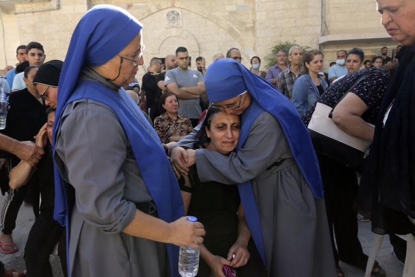 Nuns comfort a Palestinian woman as she mourns the death of a relative, killed in Israeli airstrikes that hit a church, during a funeral service in Gaza City, Friday, Oct. 20, 2023. An Israeli airstrike hit a Greek Orthodox church housing displaced Palestinians near the hospital late Thursday. The military said it had targeted a Hamas command center nearby, causing damage to a church wall. Gaza's Hamas-run Health Ministry said 16 Palestinian Christians were killed. (AP Photo/Abed Khaled)