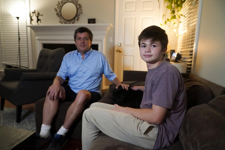 Dan Bradford, left, and his son Callum, pose for a portrait at their home, Thursday, Sept. 14, 2023, in Chapel Hill, N.C. Bradford, a transgender teen from Chapel Hill needed mental health care after overdosing on prescription drugs. He was about to be transferred to another hospital due to a significant bed shortage. A North Carolina hospital network is referring transgender psychiatric patients to treatment facilities that do not align with their gender identities. Though UNC Hospitals policy discourages the practice, administrators say a massive bed shortage is forcing them to make tough decisions. (AP Photo/Erik Verduzco)