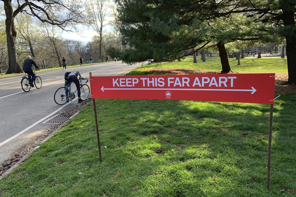 Signage urging social distancing is seen in Prospect Park in the Brooklyn borough of New York, Wednesday, April 8, 2020. While New York Gov. Andrew Cuomo said New York could be reaching a "plateau" in hospitalizations, he warned that gains are dependent on people continuing to practice social distancing. (AP Photo/Wong Maye-E)