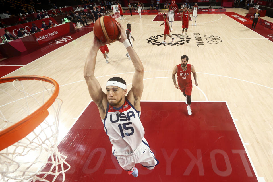 United States' Devin Booker (15) dunks the ball ahead of Iran's Mohammadsamad Nik Khahbahrami (14) during a men's basketball preliminary round game at the 2020 Summer Olympics, Wednesday, July 28, 2021, in Saitama, Japan. (Gregory Shamus/Pool Photo via AP)