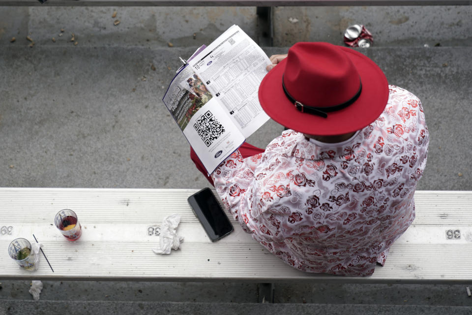 A race fan looks at his program before the 148th running of the Kentucky Derby horse race at Churchill Downs Saturday, May 7, 2022, in Louisville, Ky. (AP Photo/Charlie Riedel)