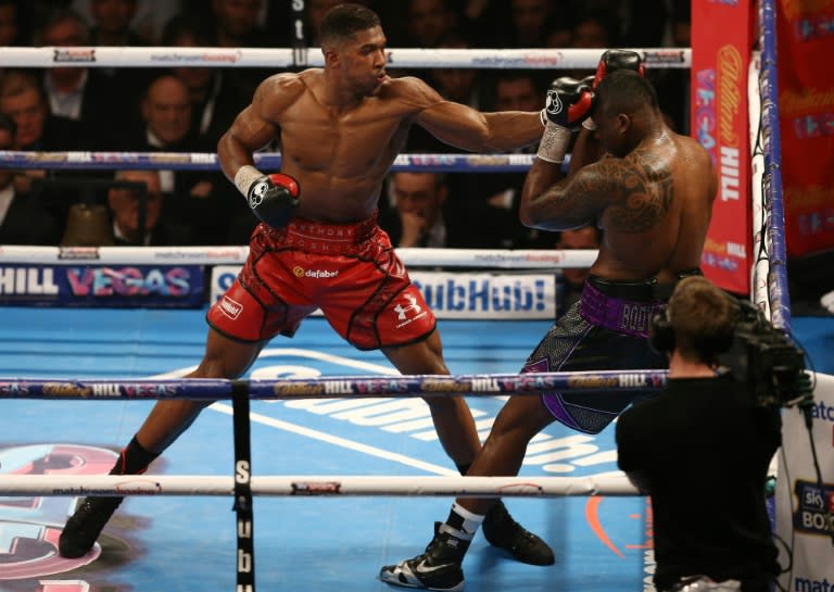 British boxers Anthony Joshua (L) keeps Dillian Whyte in the corner during their British and Commonwealth heavyweight title boxing match at the O2 arena in London on December 12, 2015