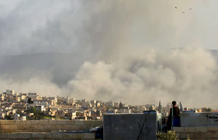 FILE PHOTO: A man watches as smoke rises after what activists said was an air strike on Atimah, Idlib province March 8, 2015. REUTERS/Ammar Abdullah/File Photo