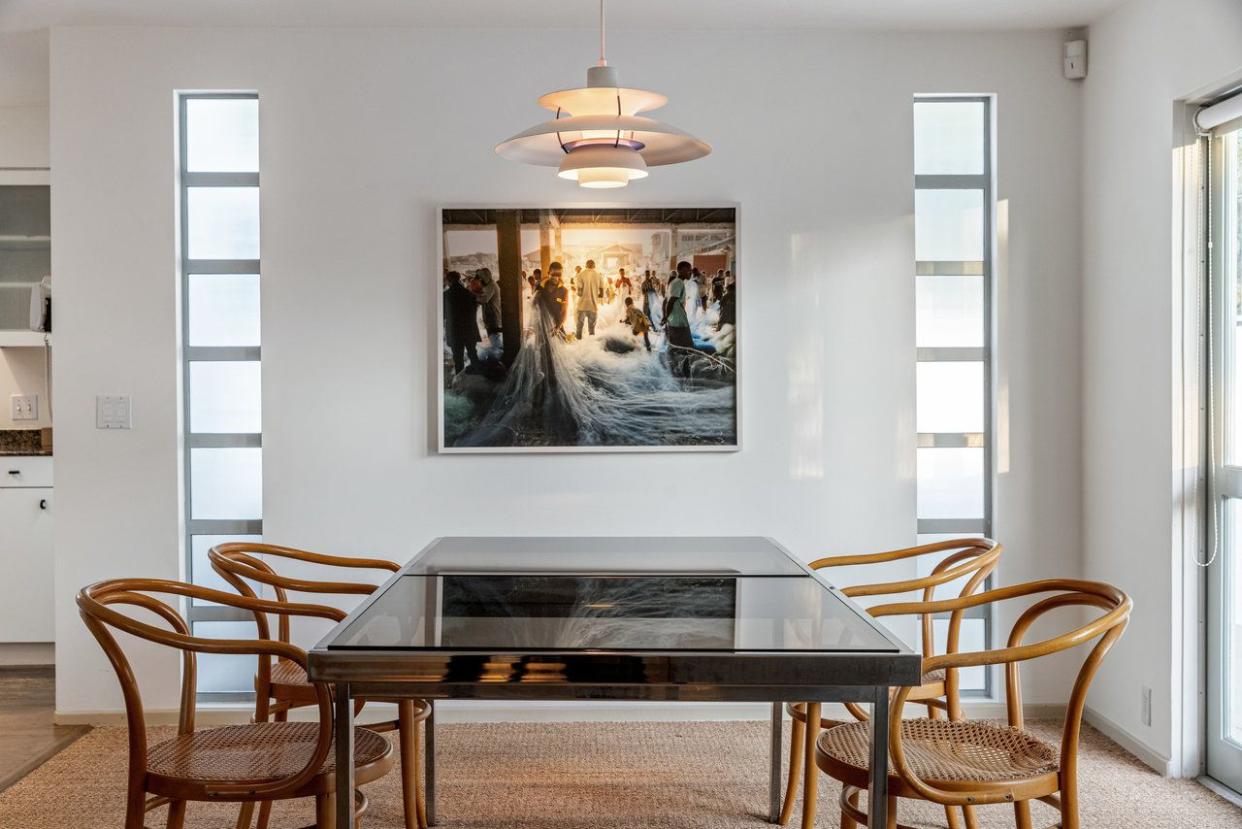 a dining room table with chairs and a painting on the wall