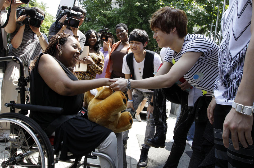 Donika Sterling from New York, left, shakes hand with Tae Min, her most favorite member of South Korean pop group SHINee after their meeting in Seoul, South Korea, Wednesday, June 20, 2012. The 15 year-old American K-pop fan, who is suffering a disease that gradually causes loss of muscle tissue and slows down parts of the body, met and sang with the boy band she idolizes. (AP Photo/Lee Jin-man)