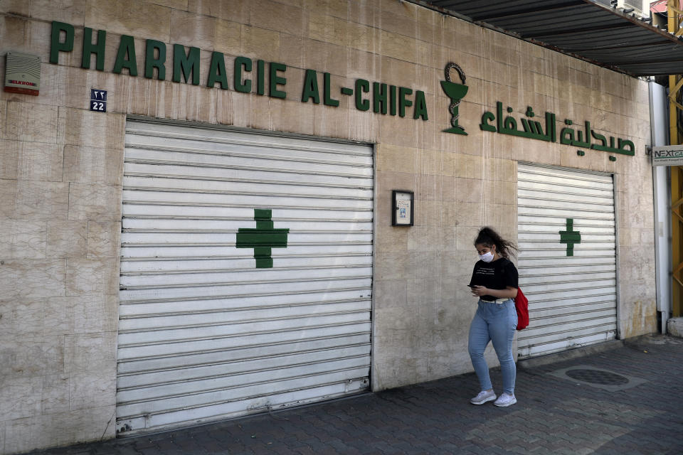 A woman passes by a closed pharmacy in Beirut, Lebanon, Friday, June 11, 2021. Pharmacies across Lebanon began a two-day strike Friday, protesting severe shortages in medicinal supplies that is increasingly putting them in confrontation with customers and patients searching for medicines. The shortages are affecting everything from medicines for chronic illnesses to pain relievers to infant milk. (AP Photo/Bilal Hussein)