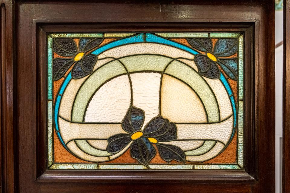 A close-up image of a stained glass window featuring dark green flowers