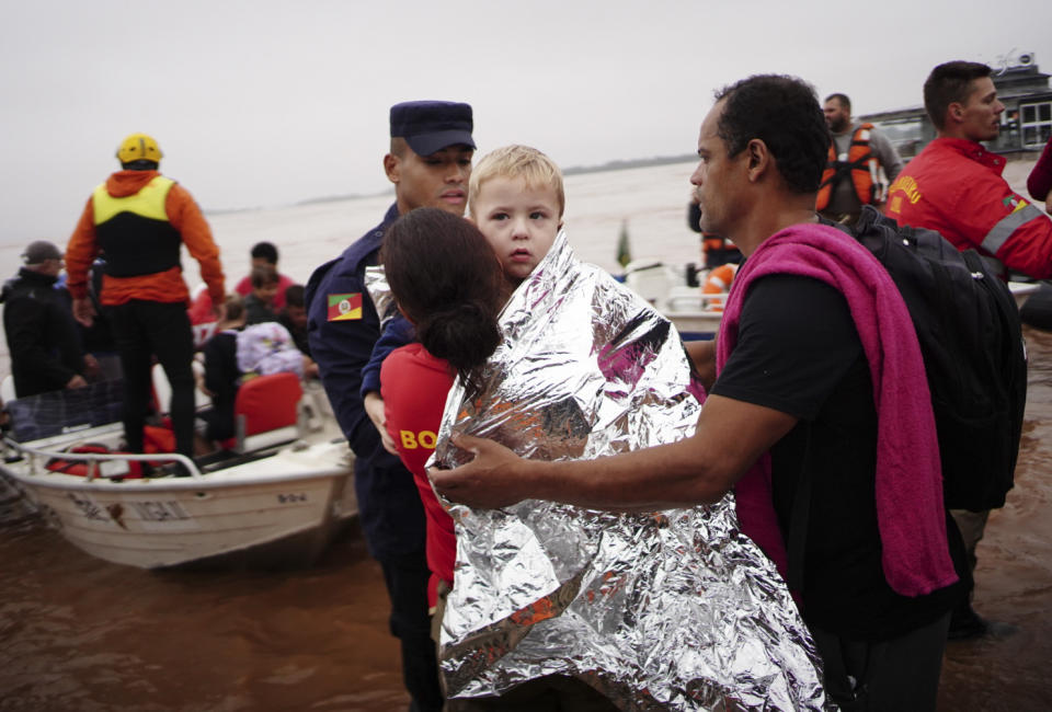 A member of the Civil Defense carries a child rescued from an area flooded by heavy rains in Porto Alegre, Rio Grande do Sul state, Brazil, Saturday, May 4, 2024. (AP Photo/Carlos Macedo)