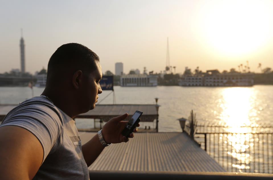 In this Sunday, Sept. 8, 2013 photo, a man checks his mobile phone by the Nile river in Cairo, Egypt. Before the 2011 revolution that started Egypt's political roller coaster, sites like the pyramids were often overcrowded with visitors and vendors, but after a summer of coup, protests and massacres, most tourist attractions are virtually deserted to the point of being serene. (AP Photo/Lefteris Pitarakis)