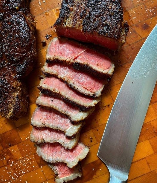 Sliced strip steak on cutting board next to knife