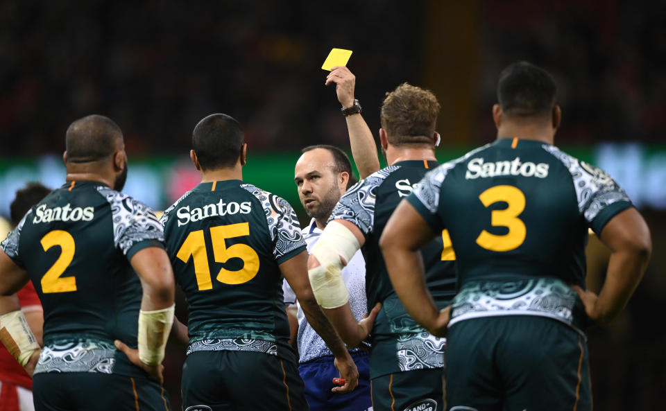 Referee Mike Adamson (pictured middle) hands Kurtley Beale a yellow card.