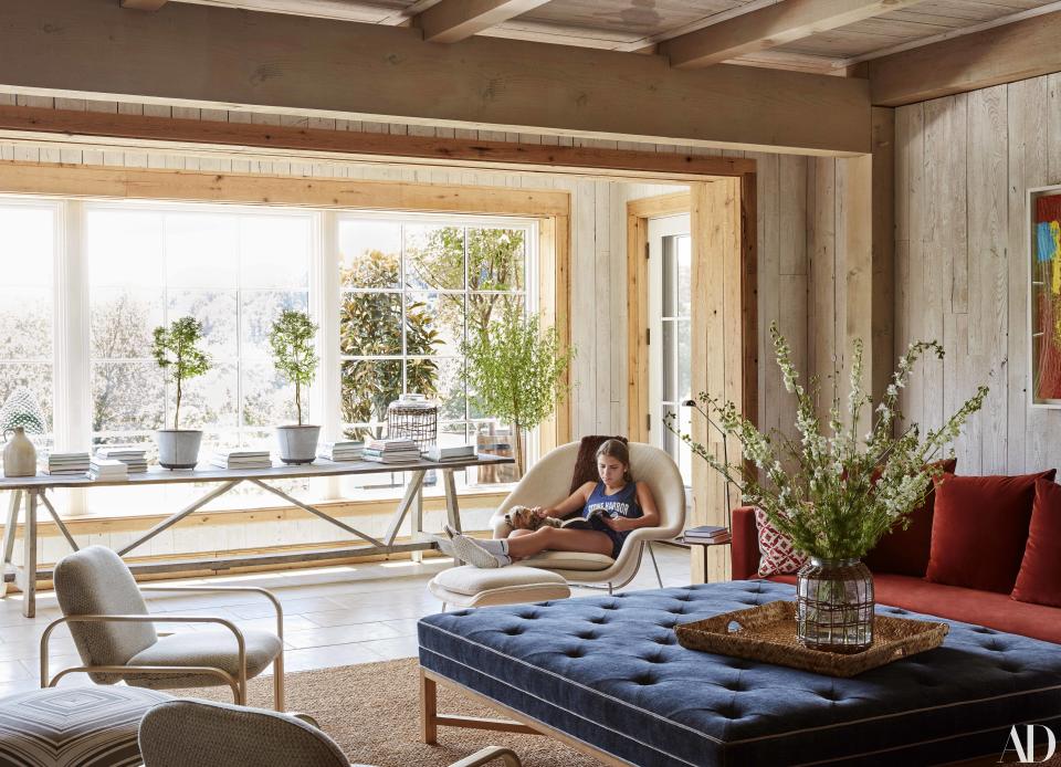 An Eero Saarinen Womb chair and ottoman in the family room. The large blue ottoman is an <a rel="nofollow noopener" href="http://www.isabellopezquesada.com/" target="_blank" data-ylk="slk:Isabel López-Quesada;elm:context_link;itc:0;sec:content-canvas" class="link ">Isabel López-Quesada</a> design.