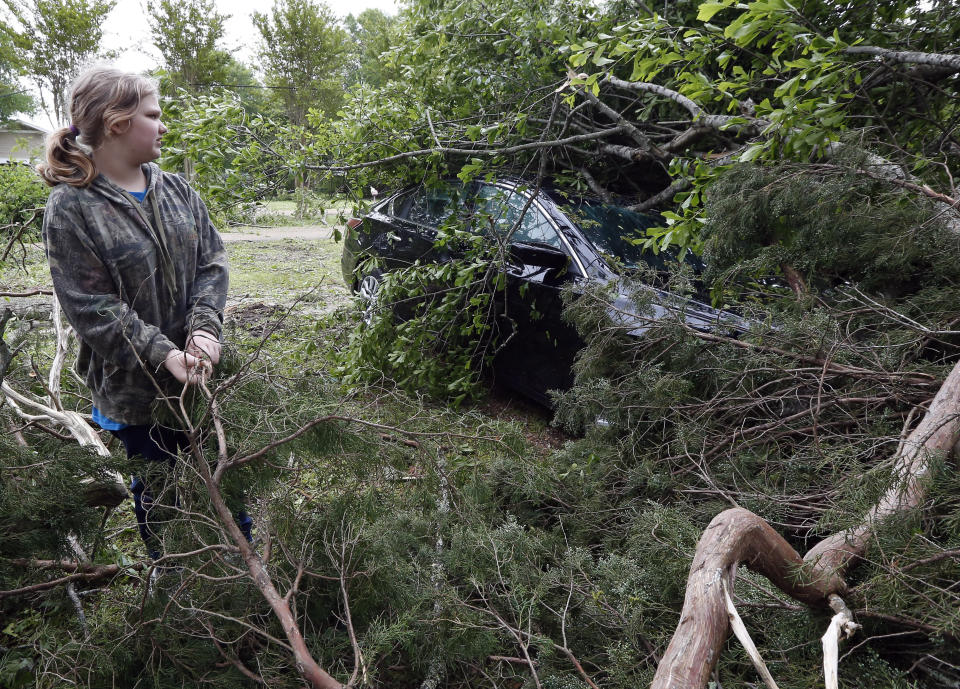 Kayla Easterling of Flora, Miss., looks at a tree-limbed covered automobile that belongs of a member of her church, Sunday, April 14, 2019. The vehicle was one of several properties damaged or destroyed by Saturday's severe weather. The storm was one of several that hit the state. (AP Photo/Rogelio V. Solis)