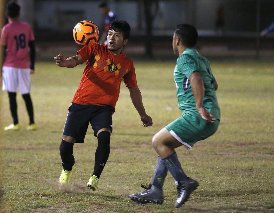 Adelfo Guillermo Martin Perez, 24, left, an arrival in the United States for three months and originally from Guatemala, controls the ball at a Maya Chapin soccer league game at a soccer league game Wednesday, April 17, 2019, in Phoenix. (AP Photo/Ross D. Franklin)