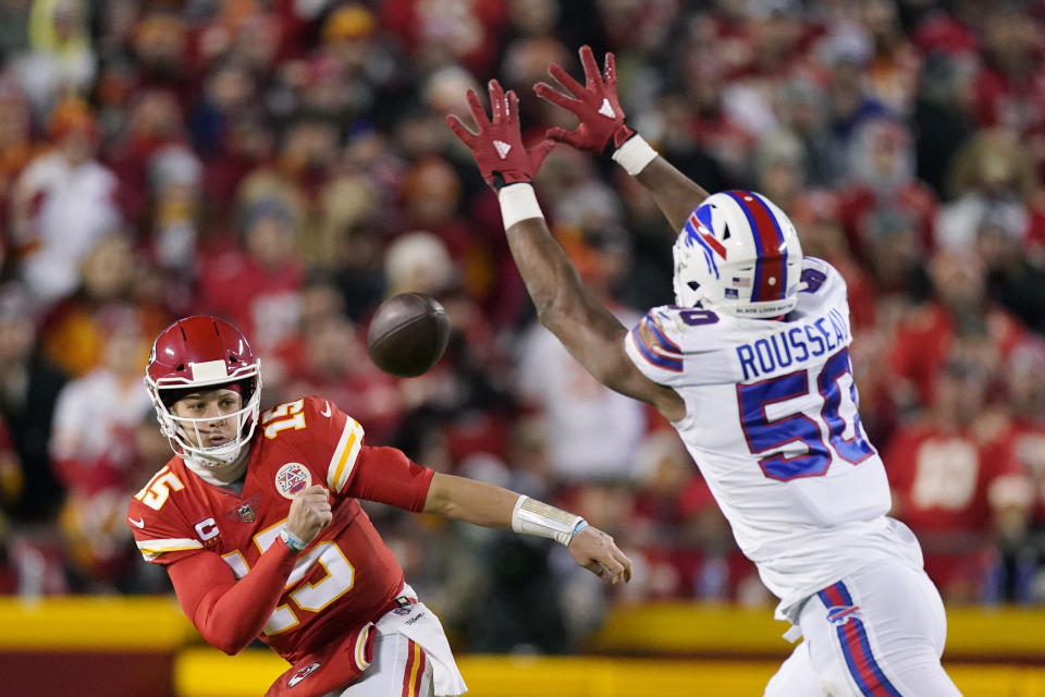 Kansas City Chiefs quarterback Patrick Mahomes (15) throws a pass around Buffalo Bills defensive end Greg Rousseau (50) during the first half of an NFL divisional round playoff football game, Sunday, Jan. 23, 2022, in Kansas City, Mo. (AP Photo/Charlie Riedel)