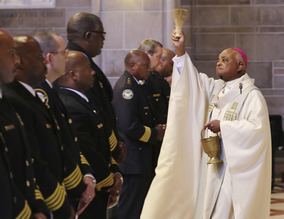 FILE - In this Sept. 11, 2015, file photo, Archbishop Wilton Gregory, right, celebrates mass and blesses the badges of the first responders as the Archdiocese of Atlanta held its first "Blue Mass" for public safety officials and first responders in Atlanta. Pope Francis on Sunday, Oct. 23, 2020, named 13 new cardinals, including Washington D.C. Archbishop Wilton Gregory, who would become the first Black U.S. prelate to earn the coveted red hat. In a surprise announcement from his studio window to faithful standing below in St. Peter’s Square, Francis said the churchmen would be elevated to a cardinal’s rank in a ceremony on Nov. 28. (Bob Andres/Atlanta Journal-Constitution via AP, File)