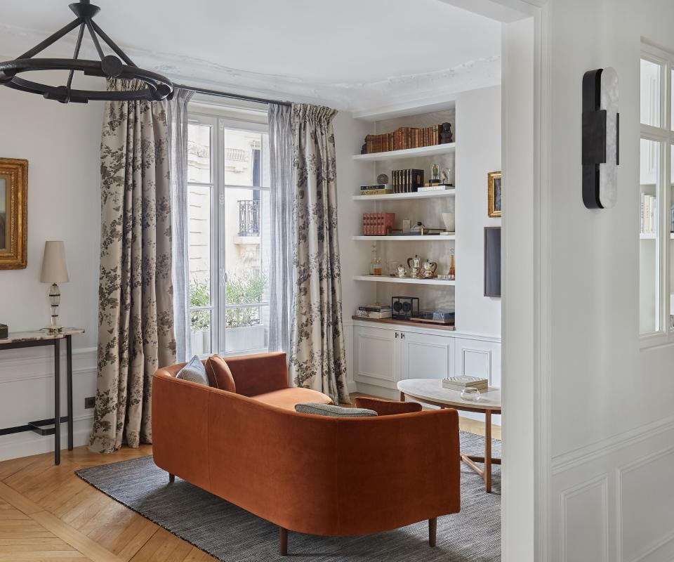 living room with partition wall and  russet sofa and period windows with patterned curtains and white walls