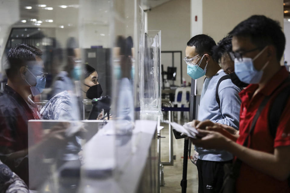 Airport officials check documents of foreign passengers as they arrive at Manila's International Airport, Philippines Thursday, Feb. 10, 2022. The Philippines lifted a nearly 2-year ban on foreign travelers Thursday in a lifesaving boost for its tourism and related industries as an omicron-fueled surge eases. (AP Photo/Basilio Sepe)