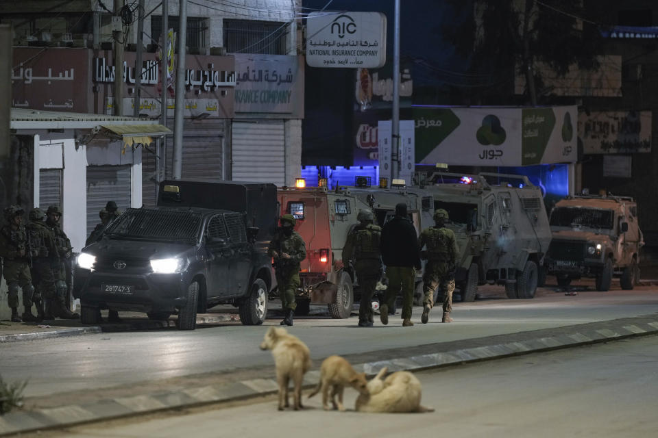 Israeli soldiers are deployed at the scene where a Palestinian gunman opened fire at soldiers in the West Bank town of Hawara, Saturday, March 25, 2023. The Israeli military said two soldiers were wounded Saturday evening in a drive-by shooting in the occupied West Bank, the latest in months-long violence between Israel and the Palestinians. The attack was the third to take place in the Palestinian town of Hawara in less than a month. A manhunt was launched as forces sealed roads leading to Hawara. (AP Photo/Majdi Mohammed)