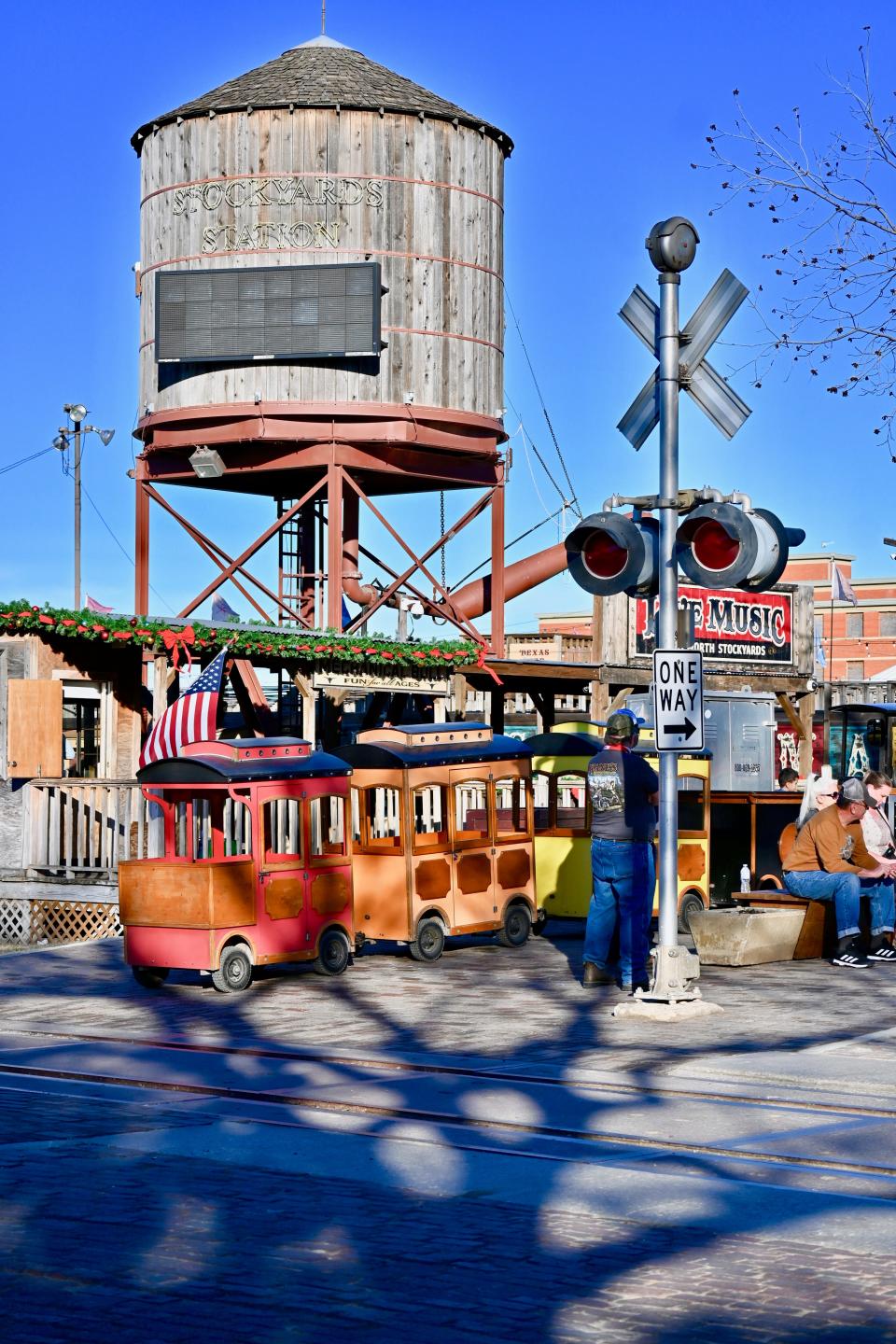 A weathered water tower and a few old trolley cars sit next to a railroad crossing.