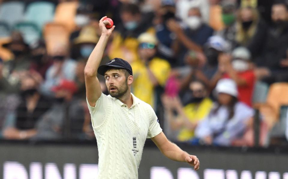 Mark Wood walks off the pitch holding the pink ball aloft - SHUTTERSTOCK