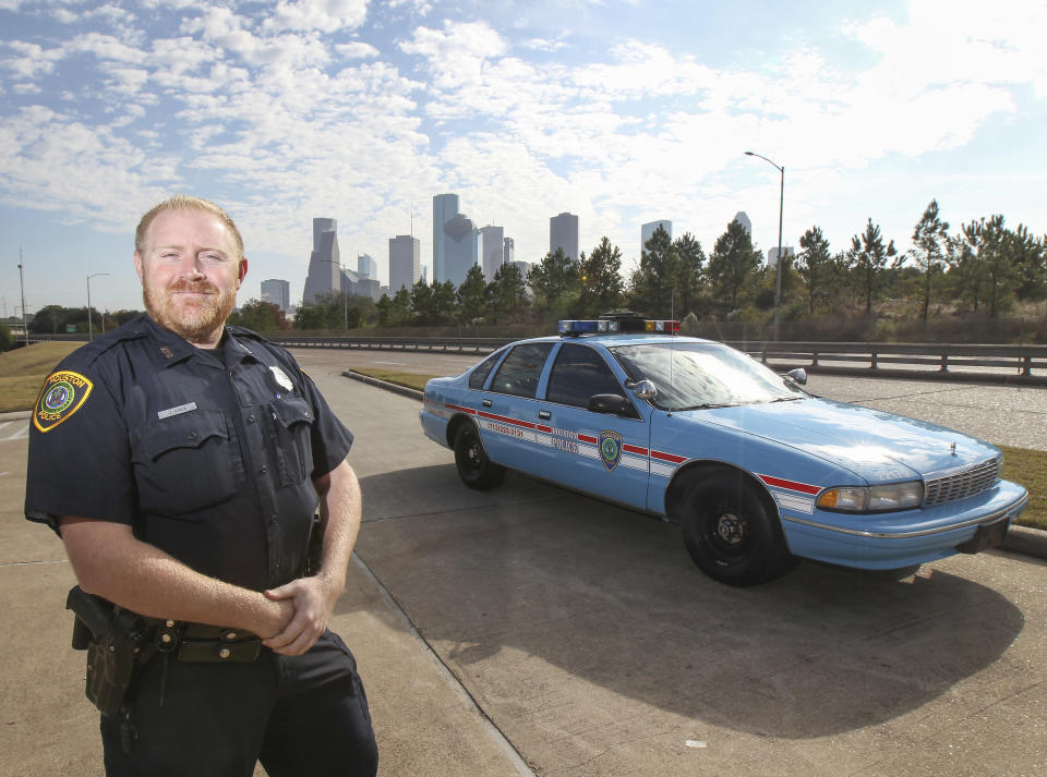 FILE - This Nov. 21, 2018 photo shows Houston police officer Jason Knox standing by a restored HPD cruiser in Houston. The Houston police department tweeted that Knox, a Tactical Flight Officer, was killed when a police helicopter crashed early Saturday, May 2, 2020 in Houston. (Steve Gonzales/Houston Chronicle via AP)