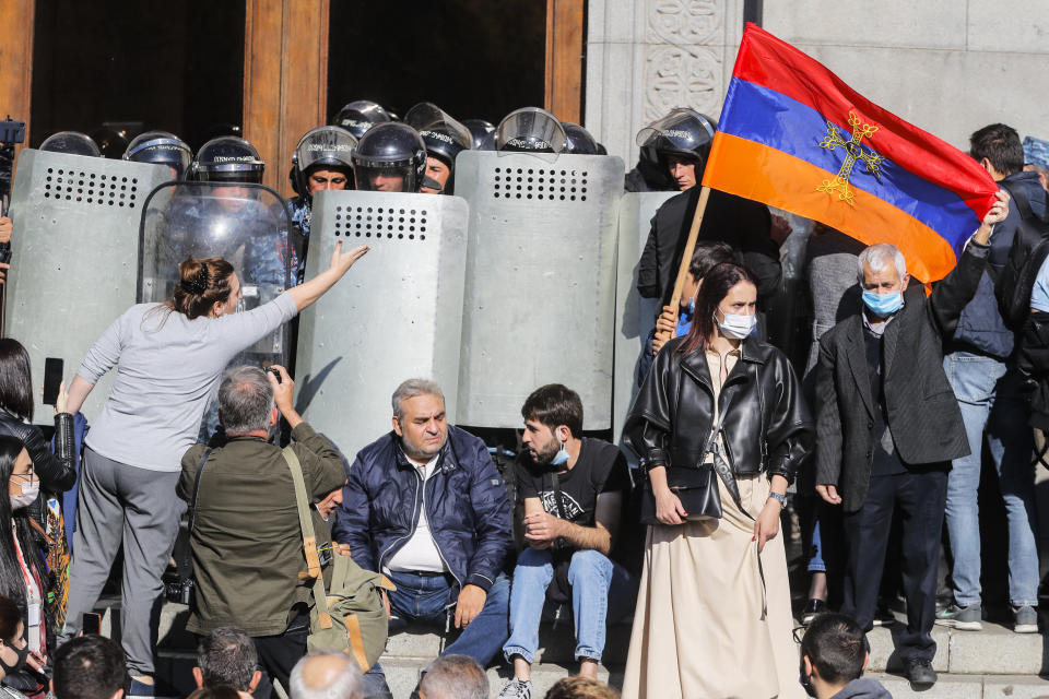 Protesters hold an Armenian national flag during a protest against an agreement to halt fighting over the Nagorno-Karabakh region, in Freedom Square in Yerevan, Armenia, Wednesday, Nov. 11, 2020. Thousands of people flooded the streets of Yerevan once again on Wednesday, protesting an agreement between Armenia and Azerbaijan to halt the fighting over Nagorno-Karabakh, which calls for deployment of nearly 2,000 Russian peacekeepers and territorial concessions. Protesters clashed with police, and scores have been detained. (AP Photo/Dmitri Lovetsky)