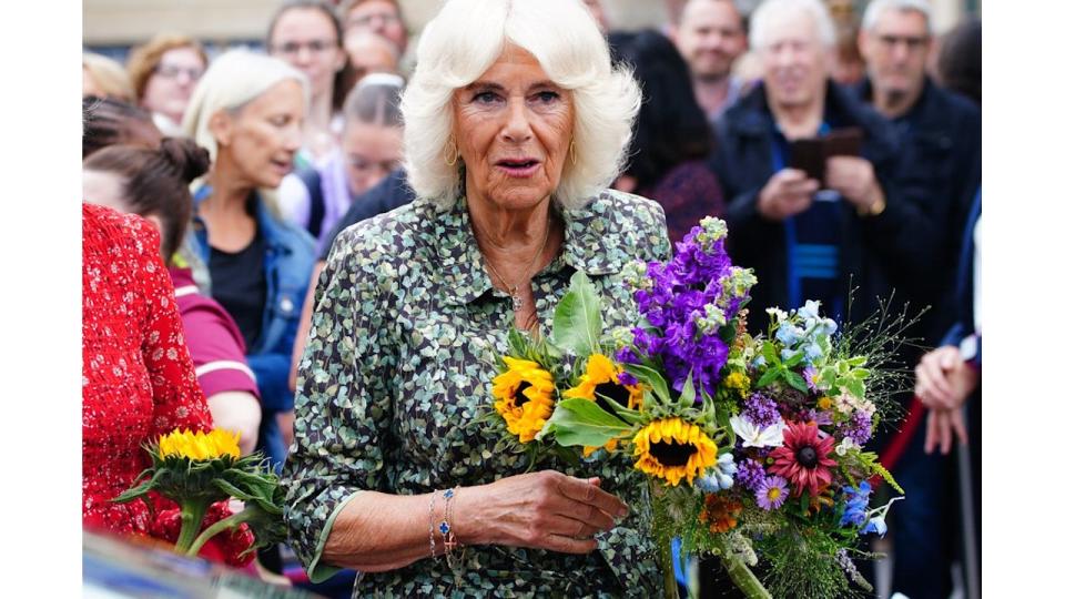 woman in green dress holding bouquet of flowers