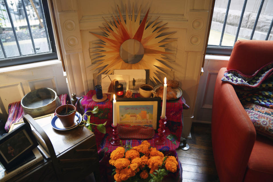 A Day of the Dead altar decorated with photographs, candles, marigolds and favorite items and foods sits in Sebastian Diaz Aguirre's living room in the Brooklyn borough of New York, Wednesday, Oct. 28, 2020. "It feels extremely comforting. I do feel I have a connection with my dad," said Diaz Aguirre, who set up the altar in remembrance of his father. (AP Photo/Emily Leshner)