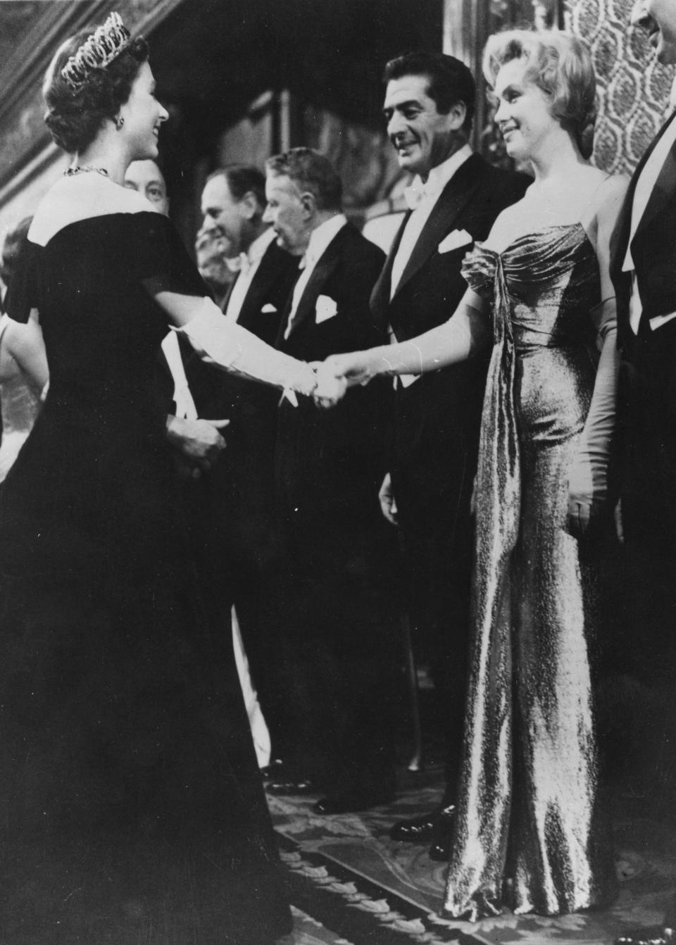 Queen Elizabeth in a black velvet dress by Norman Hartnell greets Hollywood guests such as Marilyn Monroe in 1956