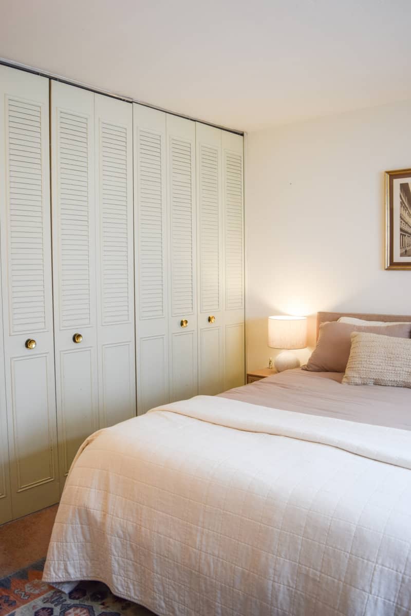 Built-in closet next to bed with decorative pillows  and framed artwork