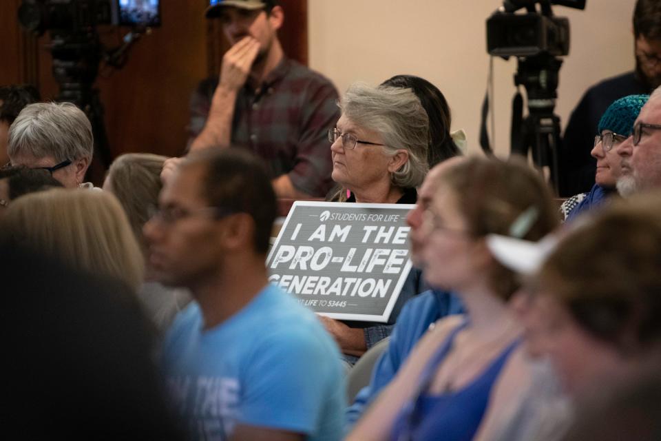 An attendee holds a sign distributed by Students for Life, a national anti-abortion organization, during a Pueblo City Council meeting on Monday, Dec. 12, 2022