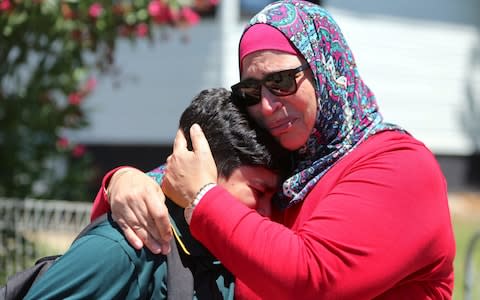 A woman hugs her son near where a vehicle crashed into a primary school classroom in the Sydney suburb of Greenacre - Credit: Reuters