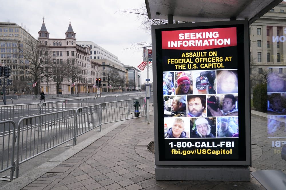 In this Jan. 15, 2021, file photo a bus stop along Pennsylvania Avenue shows a poster from the FBI in Washington. (AP Photo/Susan Walsh, File)