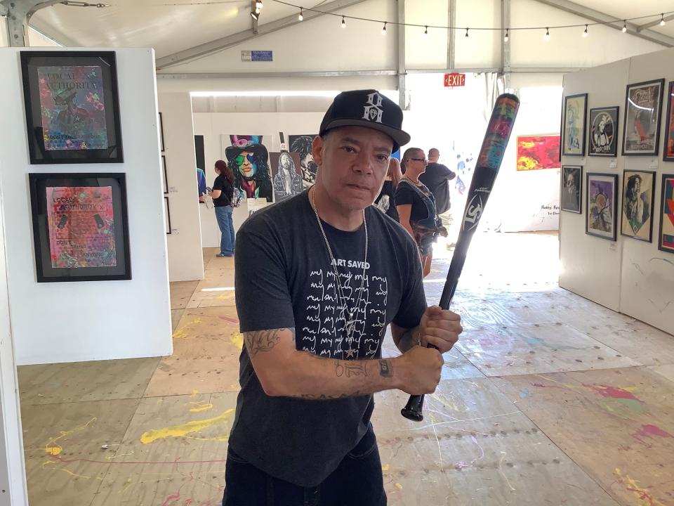 Eddie Donaldson, executive advisor for Artists for Trauma, holds a custom bat created in partnership with the Louisville Slugger Museum at the Art and Sound exhibit at Louder Than Life 2023 at the Highland Festival Grounds in Louisville on Sept. 22, 2023.