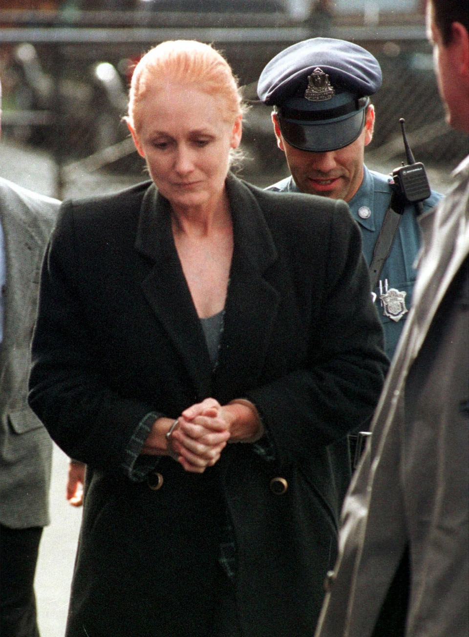 FILE - In this Nov. 8, 1999 file photo, Margaret Rudin is escorted by police into Framingham District Court in Framingham, Mass., before her arraignment on charges in connection with the shooting death of her husband. On Friday, Jan. 10, 2020, Rudin was released from prison, more than 25 years after her millionaire husband's burned body was found outside Las Vegas and 20 years after a tip generated by a "most wanted" TV show led to her arrest while living in Massachusetts with a retired firefighter she met in Mexico. (AP Photo/Michael Dwyer, File)