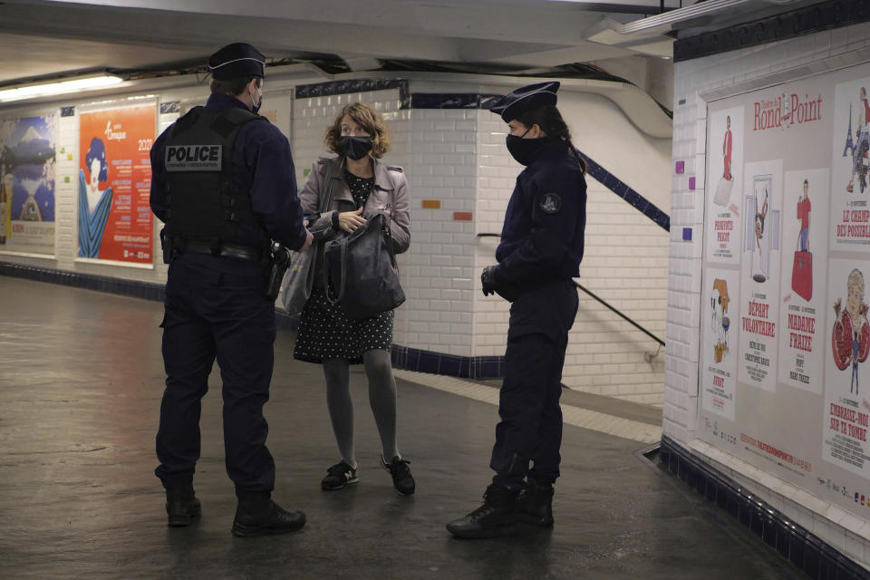 Policemen controls a commuters in the Paris subway, Friday, Oct. 30, 2020. France re-imposed a monthlong nationwide lockdown Friday aimed at slowing the spread of the virus, closing all non-essential business and forbidding people from going beyond one kilometer from their homes except to go to school or a few other essential reasons. (AP Photo/Thibault Camus)