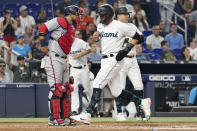 Miami Marlins' Miguel Rojas, right, scores past Washington Nationals catcher Keibert Ruiz, left, on a sacrifice fly by Garrett Cooper during the third inning of a baseball game, Wednesday, May 18, 2022, in Miami. (AP Photo/Lynne Sladky)
