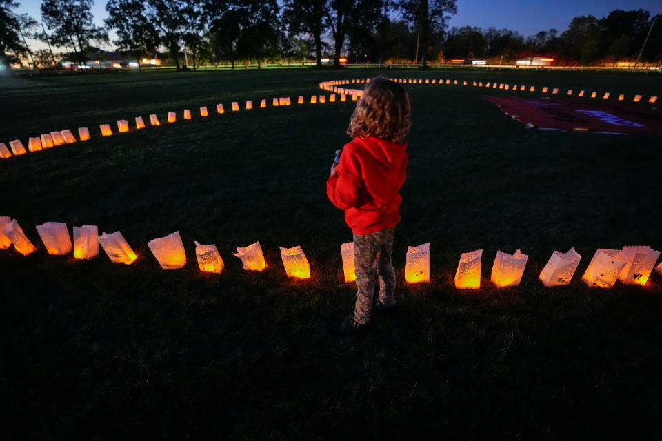 A child stands nexto to candles placed around a banner during a vigil on Canada's first National Day for Truth and Reconciliation, honouring the lost children and survivors of Indigenous residential schools, their families and communities, at Chiefswood Park in Ohsweken, Ontario, Canada September 30, 2021. REUTERS/Carlos Osorio