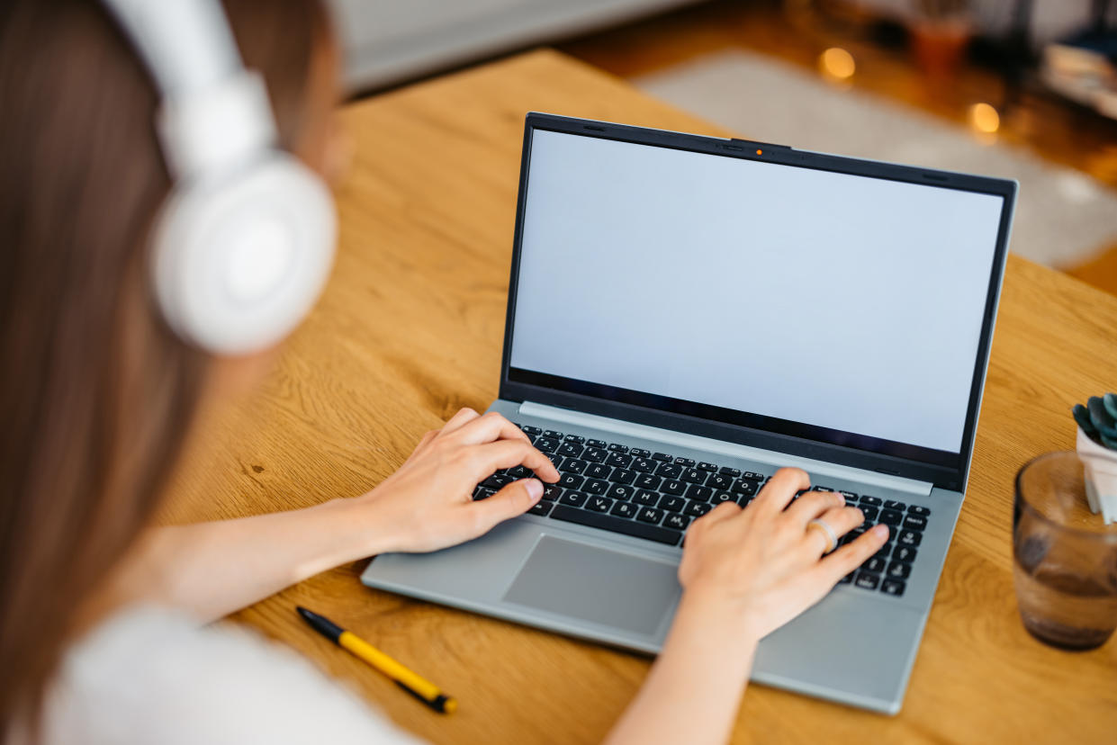 woman listening to music and working on a laptop at home, while sitting in the home office; amazon laptop