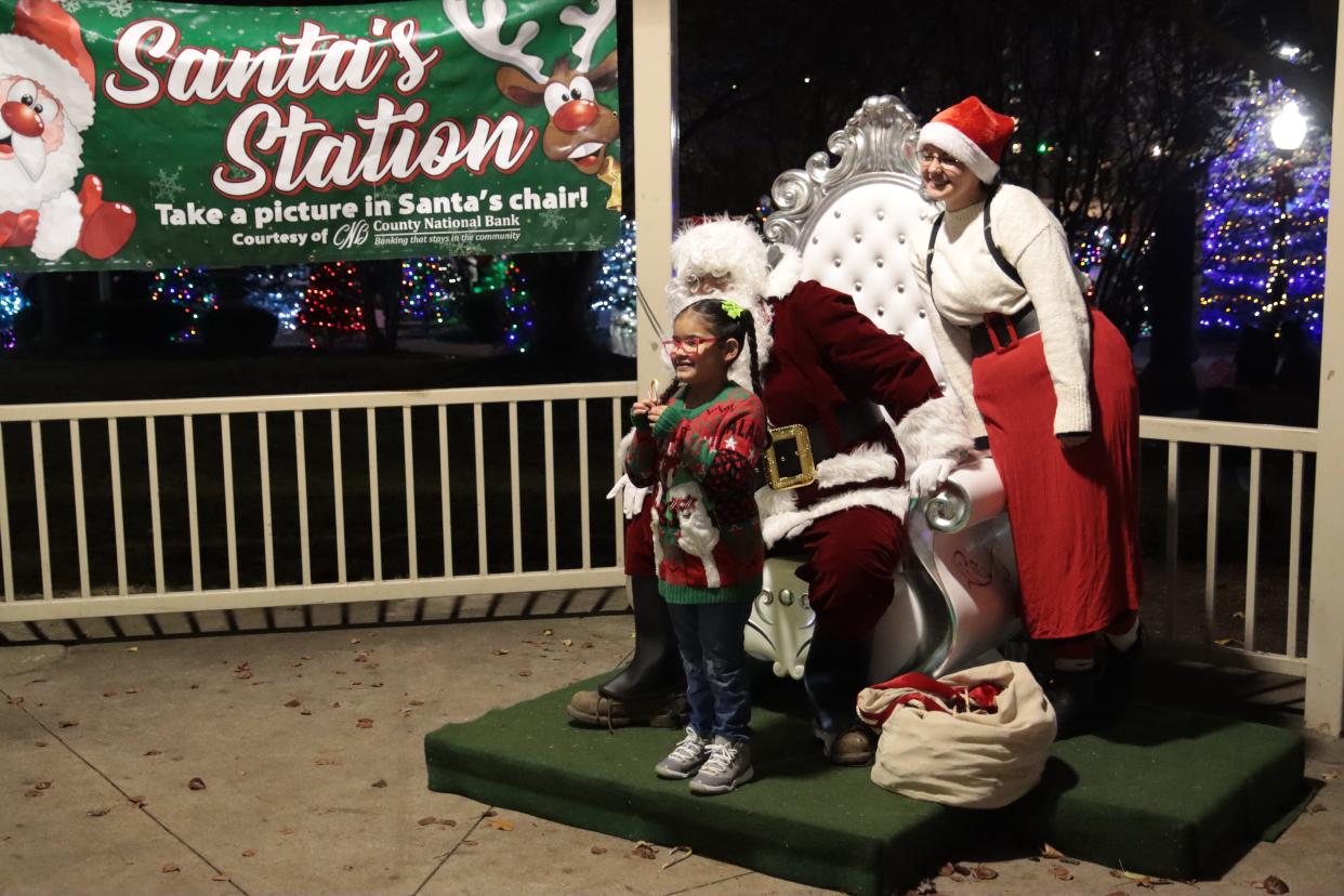 Kamila Martinez, 6, of Adrian poses for a photo with Santa and Mrs. Claus Friday, Dec. 8, 2023, after the Comstock Christmas Riverwalk lighting in Adrian.