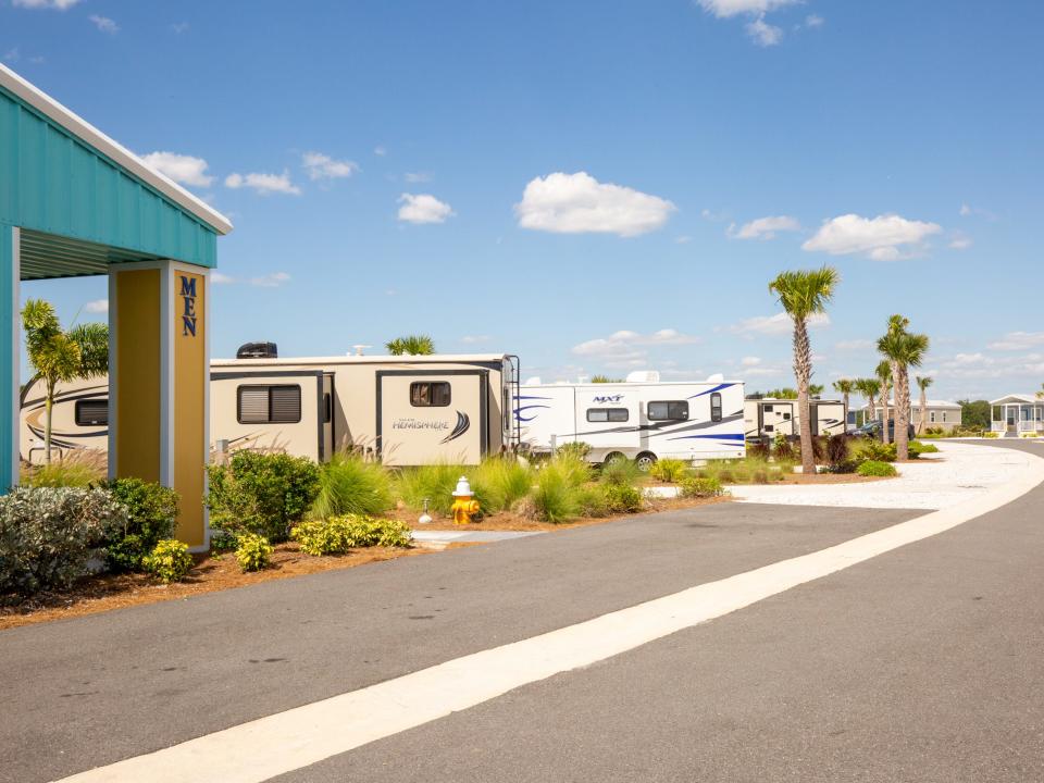 RVs parked at a RV park among palm trees.