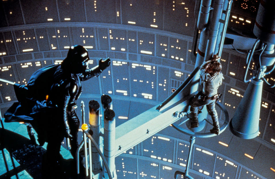 Darth Vader reaches out his hand to Mark Hamill who is hanging onto a pole
