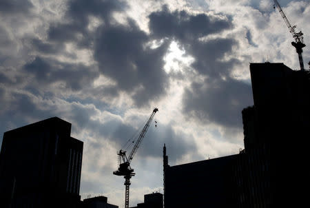 Cranes at a construction site are silhouetted at a commercial area in Tokyo, Japan, August 12, 2016. Picture taken on August 12, 2016. REUTERS/Kim Kyung-Hoon