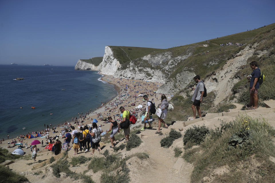 People make their way to Durdle Door Beach, as the public are being reminded to practice social distancing following the relaxation of coronavirus lockdown restrictions, near Lulworth in Dorset, England, Saturday, May 30, 2020. (Andrew Matthews/PA via AP)